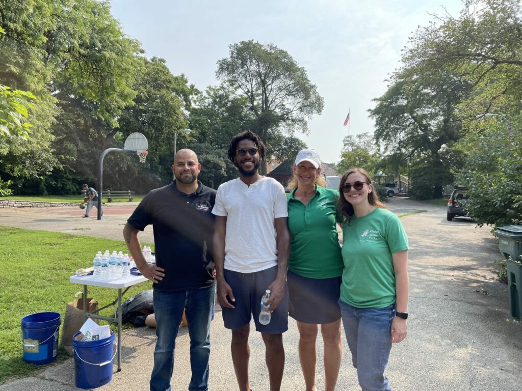 Alder Andre Vasquez and a group of 40th Ward community members smile in a sunny park.