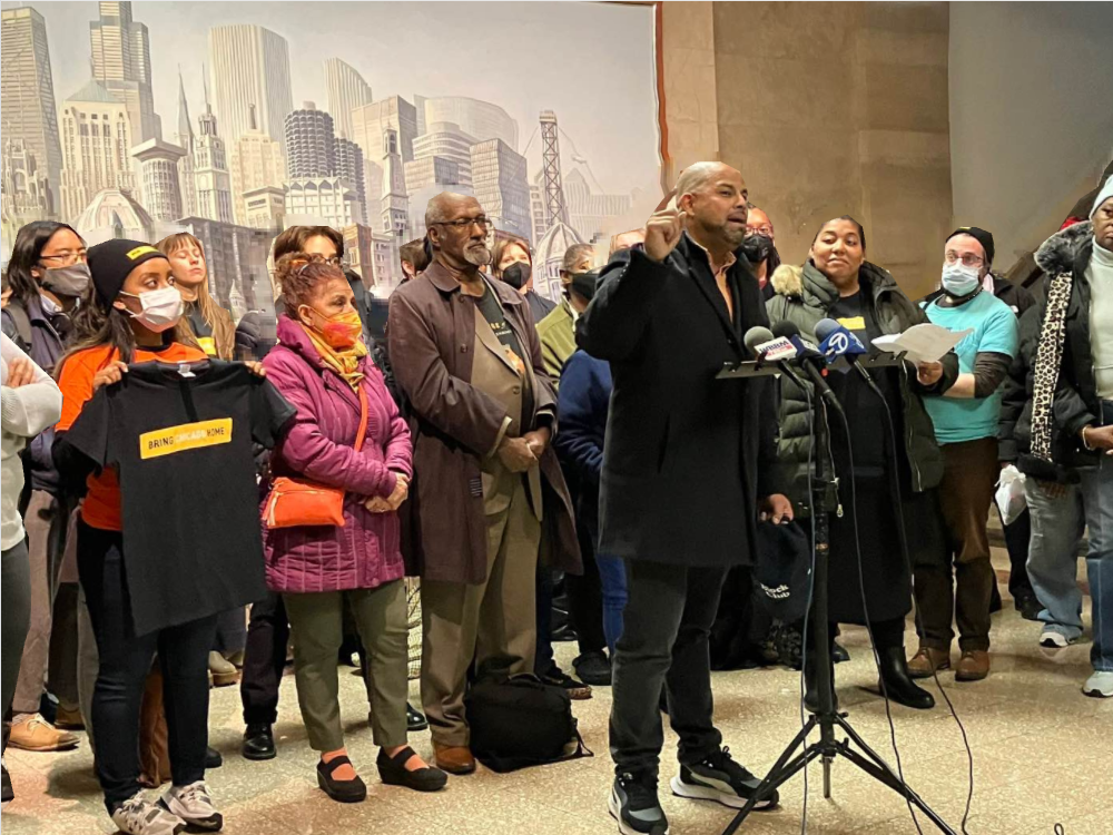 Alder Andre Vasquez stands with a crowd at City Hall to discuss Bring Chicgao Home