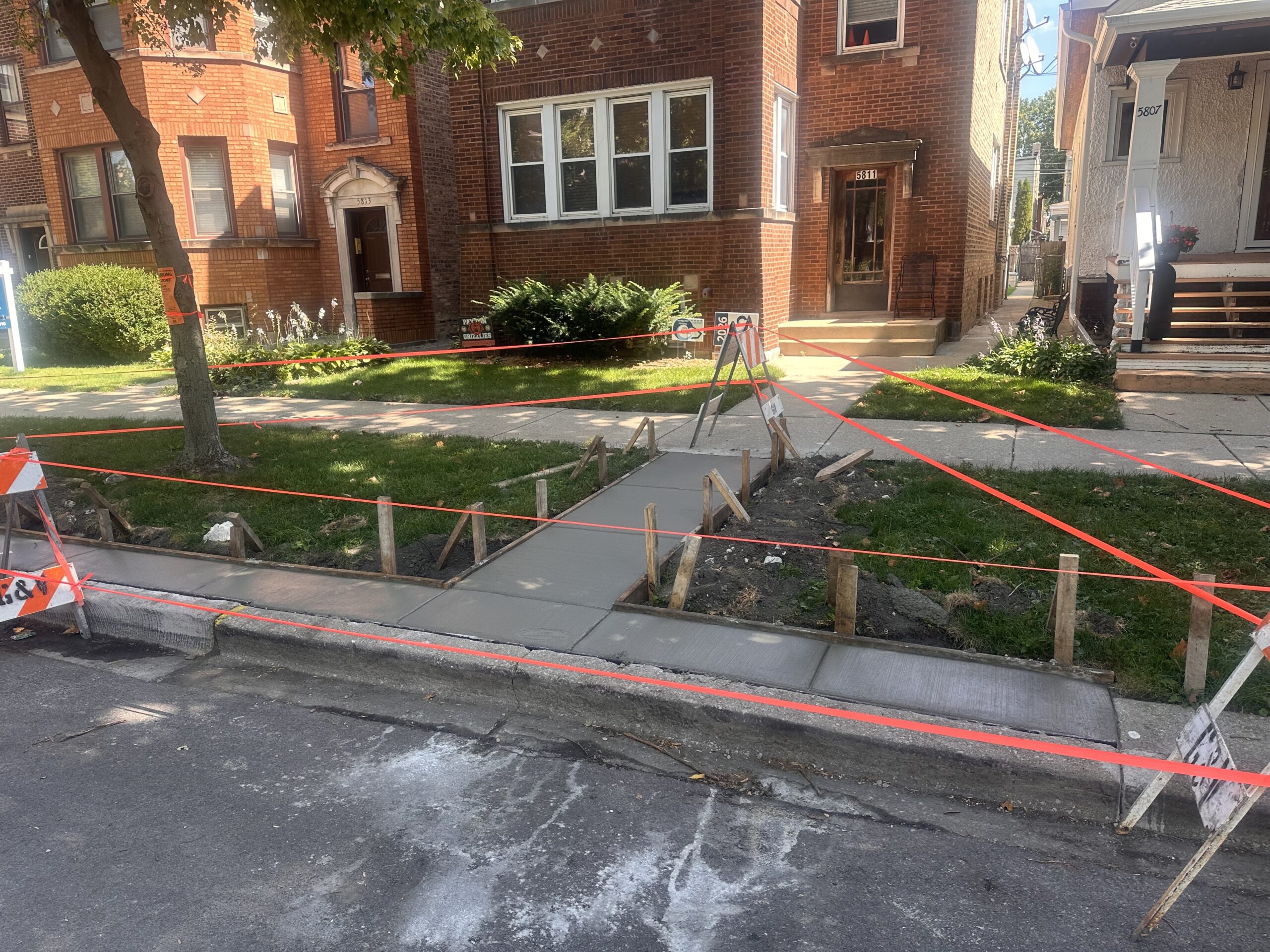 sidewalk in front of a brick multi-unit in the process of being replaced