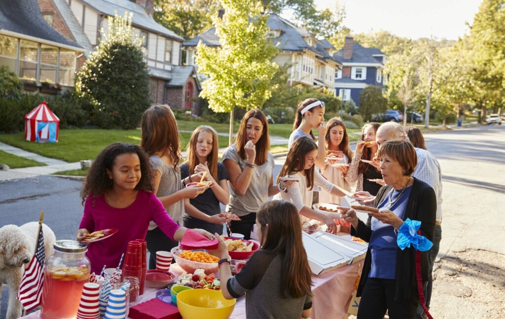 A group of neighbors enjoying themselves outside at their block party