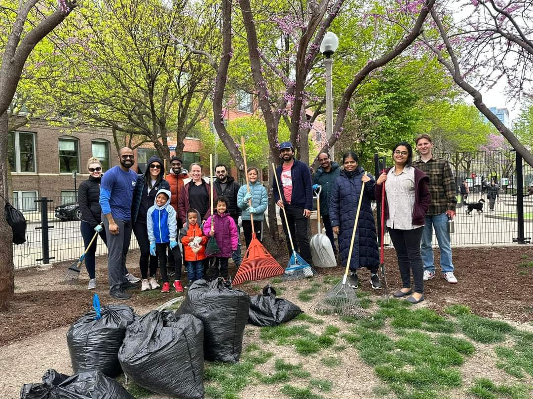 Park clean up volunteers smiling with rakes and bags of garbage they collected.