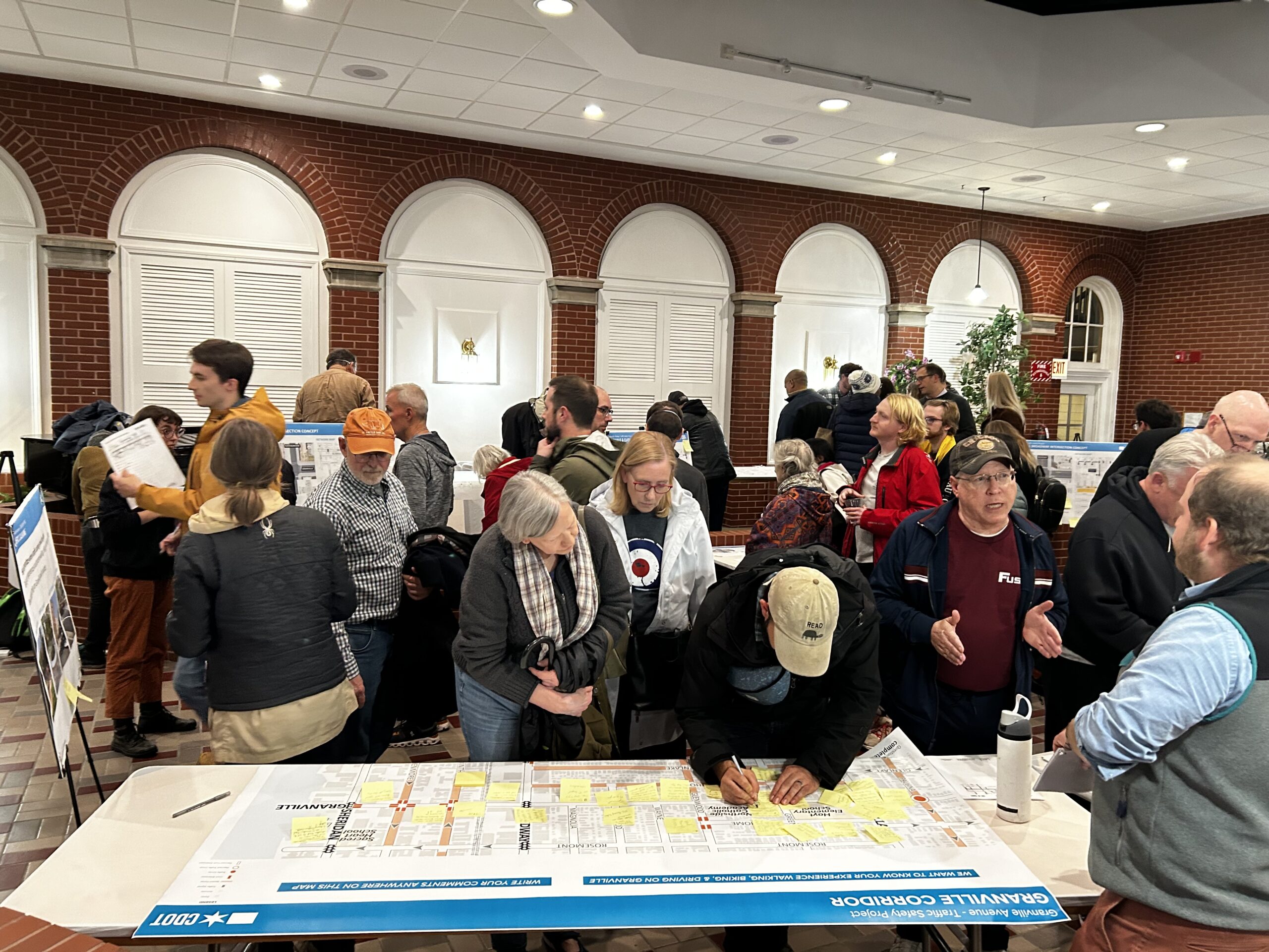 A crowd of people makes notes on a large map of Granville Avenue at the Granville traffic safety meeting